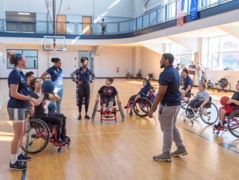 Students working with kids in wheelchairs in ODU gym