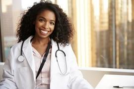 Portrait Of Smiling Female Doctor Wearing White Coat With St