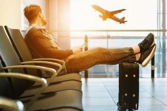 Man sitting in airport watching plane take off out the windo